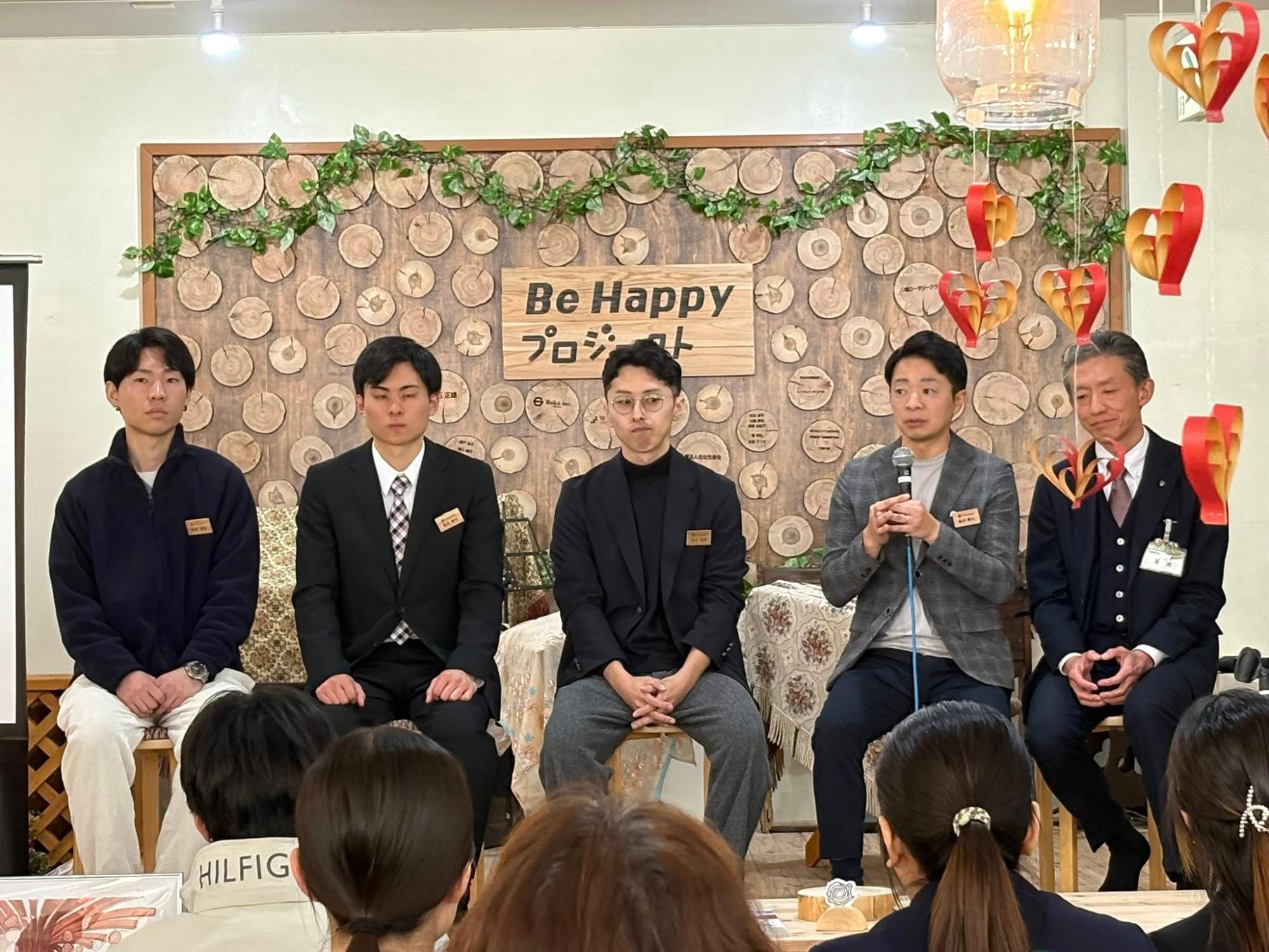 COCO RiNOVEのメンバー、先生、支援会社 大英産業社員、八幡東区 区長。後ろに掲示されているのは支援者の方々の社名や個人名が書かれた木材プレート。